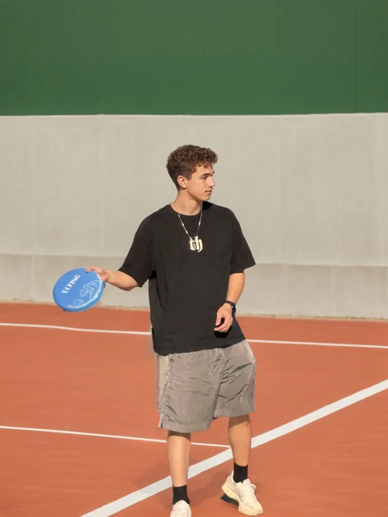 Blue EVA molded frisbee held on an outdoor court