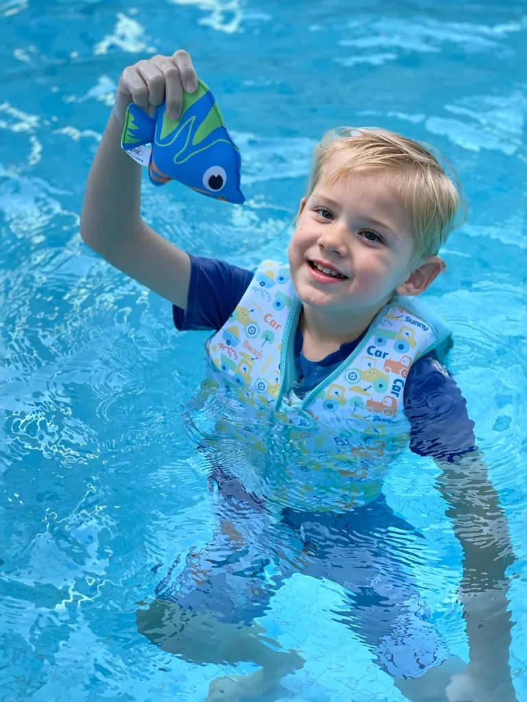 Child holding a neoprene diving toy in a swimming pool