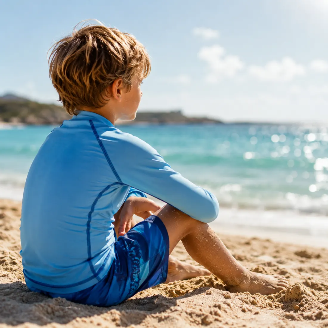 Child wearing blue rash guard in bright beach sunlight